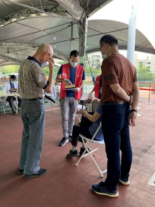 MAX（白碩）在疫苗站，用流利中文幫助長輩檢視、填寫相關文件。